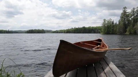 Wooden Canoe on a dock with slow motion water Stock Footage
