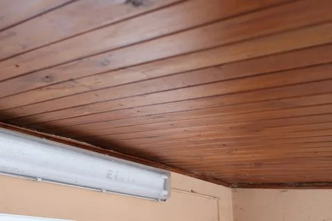 Wooden ceiling with fluorescent light fixture in a corner of a room Stock Photos