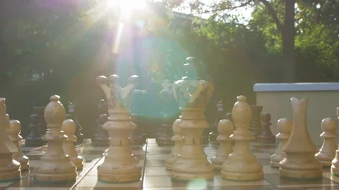 Wooden chess game on a table in a camera slide from right to left against sun Stock Footage 118720291