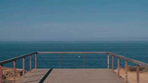 Wooden cliff-top viewpoint railing facing the calm Atlantic, Portugal Stock Footage 346479916