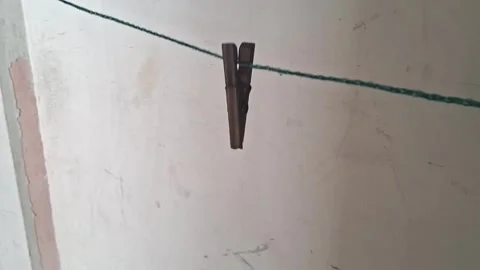 Wooden clothespin hanging on a thin string in motion video footage 動画素材 337844156