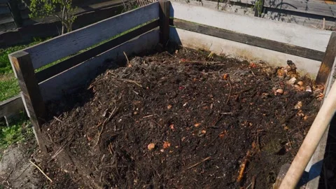 Wooden compost bin filled with dark organic compost and food scraps in the Vidéo 343239098