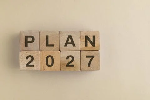 Wooden cube with 2027 PLAN text isolated on a paper background, representin.. Stock Photos