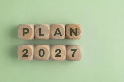 Wooden cube with 2027 PLAN text isolated on a paper background, representin.. Stock Photos