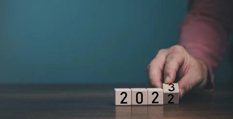 Wooden cube block flipping countdown from 2022 to 2023 on blue background, pr Stock Photos
