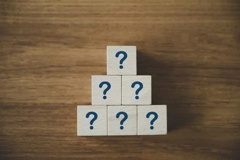 Wooden cube block shape stacking with sign question mark symbol on wood table Stock Photos