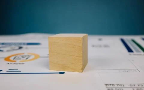 Wooden cube lying on a stack of documents on a blue background 스톡 사진
