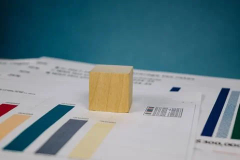 Wooden cube lying on a stack of documents on a blue background 스톡 사진