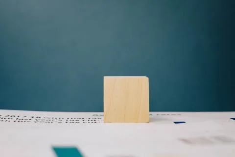 Wooden cube lying on a stack of documents on a blue background Foto stock