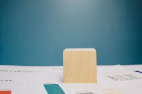 Wooden cube lying on a stack of documents on a blue background 스톡 사진