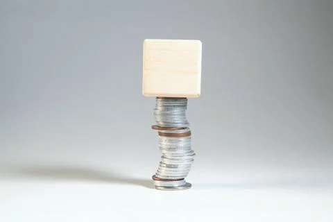 Wooden cube on stack of coins on white background, business concept 库存照片