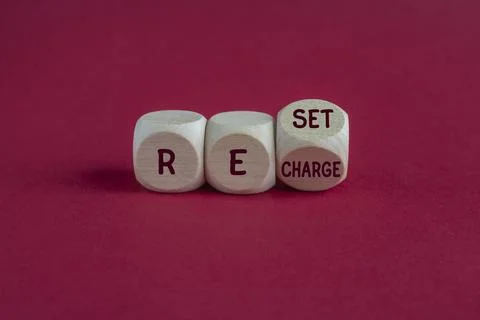 Wooden cubes form the expression Reset Recharge. Beautiful red background. Foto stock