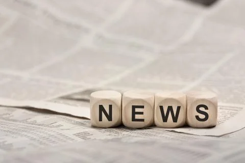 Wooden cubes on newspaper forming word NEWS Stock Photos