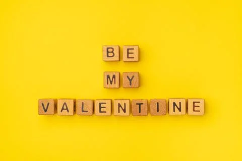 Wooden cubes with the phrase Be My Valentine on an empty colorful yellow Stock Photos