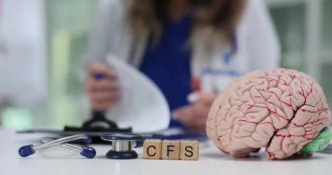 Wooden cubes spell CFS placed near brain model on clinic desk Stock Footage 313293391