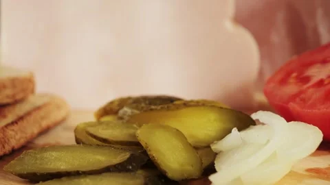 Wooden cutting board with bread, ham, onion, canned cucumber, sliced tomatoes Stock Footage 318747443