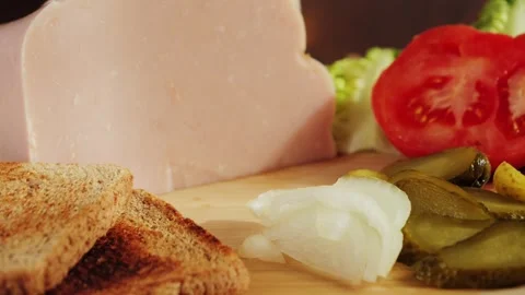 Wooden cutting board with bread, ham, onion, canned cucumber, sliced tomatoes Stock-Footage 335140538