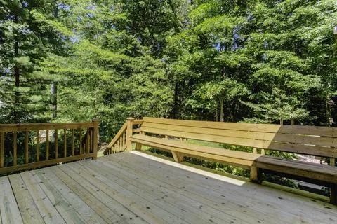 Wooden Deck With Built-In Bench Seating Amidst Lush Forest Greenery. Stock Photos