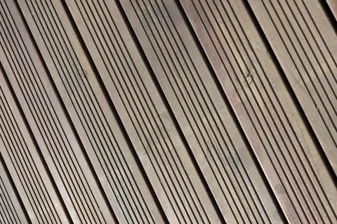 Wooden deck flooring features parallel grooves and lines, arranged diagonally 库存照片