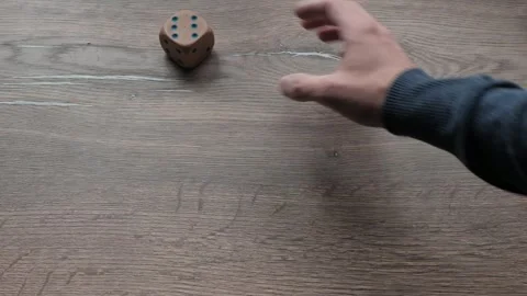 Wooden die rolling across rustic tabletop with hand release Stock Footage 341366228