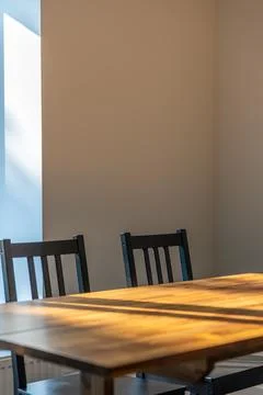 Wooden dining table in sunlight. Simple home interior with copy space. Stock Photos