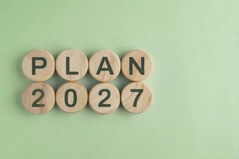 Wooden disk with 2027 PLAN text isolated on a paper background, representin.. Stock Photos
