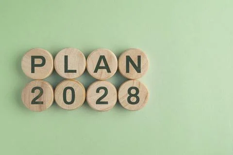 Wooden disk with 2028 PLAN text isolated on a paper background, representin.. Stock Photos
