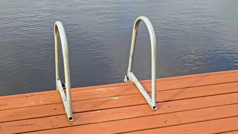 A wooden dock with a pair of metal steps, perfect for water or beach scenes Stock Footage 345988007
