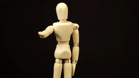 The wooden doll pulls its arm forward and rotates 360 degrees on a black Stock Footage 119791093