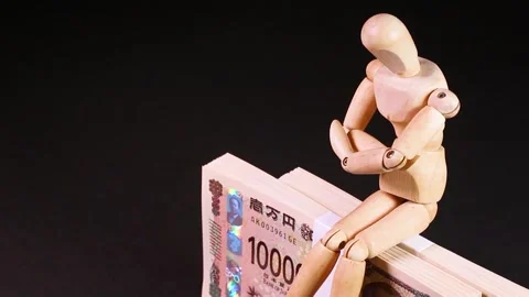 Wooden doll sitting on a stack of bills, rotating Stock Footage 312975408