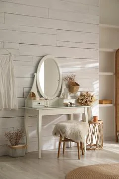 Wooden dressing table with decorative elements and makeup products in room. I Stock Photos