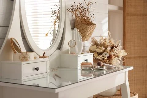 Wooden dressing table with decorative elements and makeup products in room Stock Photos