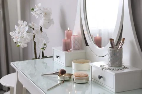 Wooden dressing table with decorative elements and makeup products in room Stock Photos