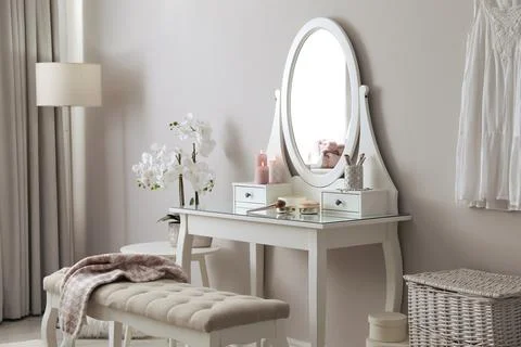 Wooden dressing table with decorative elements and makeup products in room. I Stock Photos