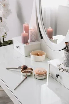 Wooden dressing table with decorative elements and makeup products in room Stock Photos