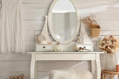 Wooden dressing table with decorative elements and makeup products in room Stock Photos