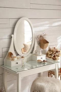 Wooden dressing table with decorative elements and makeup products in room. I Stock Photos
