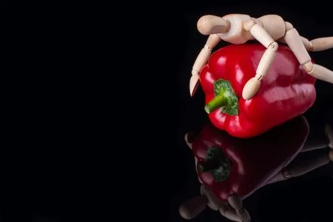 Wooden dummy hugs a pepper. Stock Photos