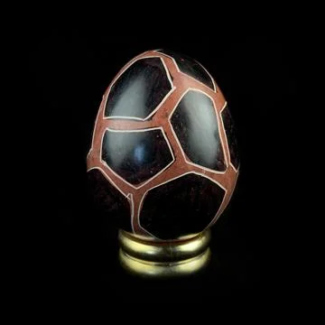 Wooden Easter egg with floral patterns on isolated black background 库存照片