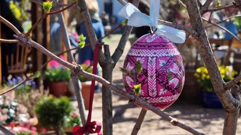 Wooden Easter egg painted with bright patterns is hung on a ribbon Stock Footage 332154212