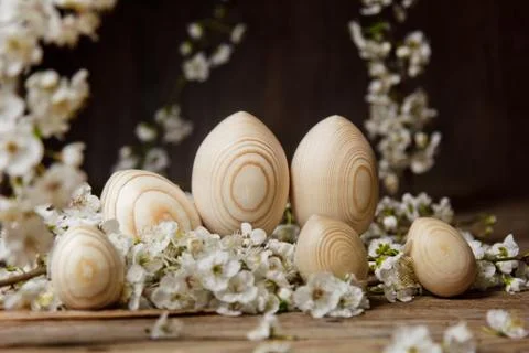 Wooden easter eggs among flowering cherry branches on a rustic table. symboli Stock Photos