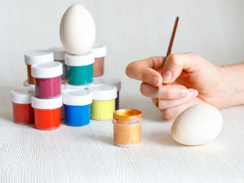 Wooden Easter eggs, multi-colored paints and hand holding brush for decorating Foto stock