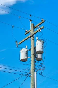 Wooden electricty pole with mounted transformators on blue sky background Stock Photos