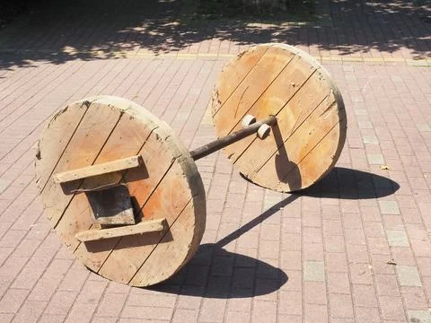 Wooden empty cable spool stands on paving slabs on a sunny day Stock Photos