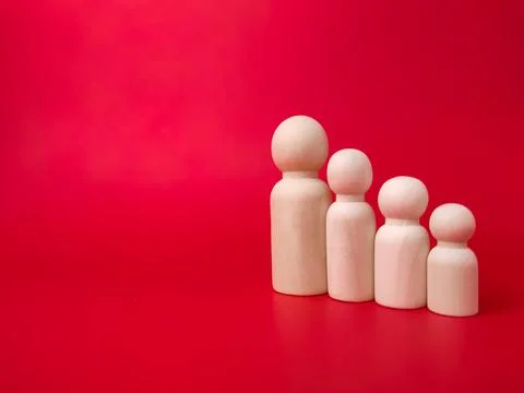 Wooden figures lined up according to their respective heights on red background Stock Photos