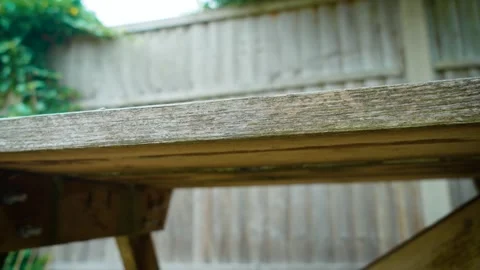 Wooden garden table standing in backyard patio beside privacy fence. Rustic Video stock 336546759
