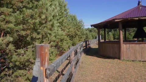A wooden gazebo near a wooden fence behind which there is a forest Stock Footage