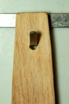 A wooden handle with a rectangular hole for hanging tools on a metal rail 스톡 사진