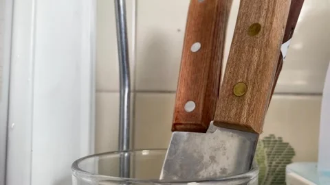 Wooden handle sharp knife close up view on kitchen sink inside glass Видео 250439556