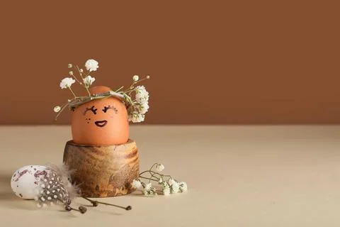 Wooden holder of creative Easter egg with flowers on beige table near brown w Stock Photos